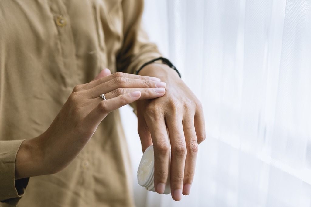 Argila preta, para que serve. Pessoa passando hidratante sobre as mãos.