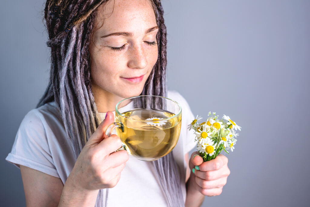 Para que serve chá de canela-de-velho, mulher sintindo-se confortável tomando chá