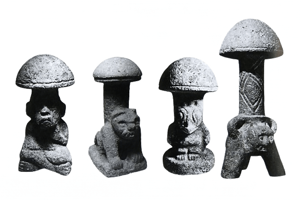 Quatro estátuas de pedra pré-colombianas representando diferentes criaturas com chapéus de cogumelo (Psilocybe) em suas cabeças. Cada estátua tem cerca de 30 cm de altura.